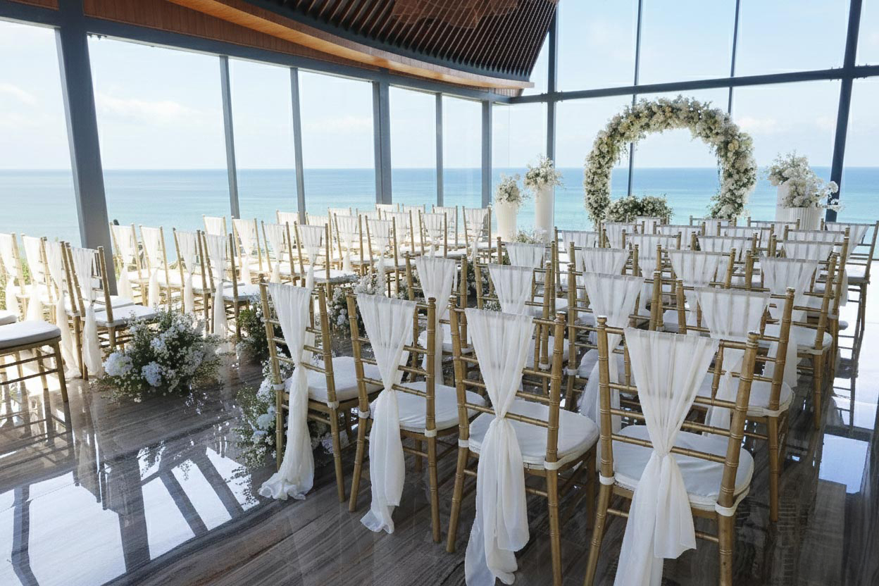 Gold chiavari chairs with white chiffon above the sea